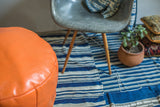 Tangerine orange leather pouf with embossed fleur de lis and floral patterns.