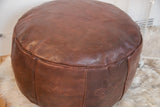Close-up of dark whiskey leather pouf, distressed texture, fleur de lis and fan stenciling.