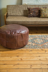 Whiskey brown leather Moroccan pouf with embossed fleur de lis patterns.
