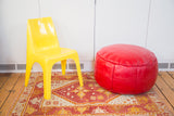 Cherry red leather pouf ottoman with embossed fleur de lis and floral fan stenciling.