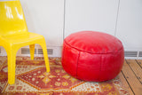 Cherry red leather pouf featuring fleur de lis and floral fan stenciling.