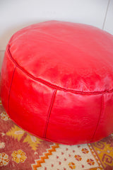 Cherry red leather Moroccan pouf with embossed fleur de lis and flower fan patterns.