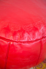 Cherry red Moroccan pouf with stenciled flower fan motifs and textured leather.