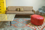 Antique Revival cranberry red leather pouf with distressed texture and lacing.