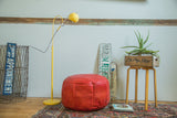 Cranberry red leather pouf ottoman with fleur de lis and flower fan stenciling.