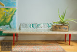 Handmade Mod Sled coffee table with a glass top, slatted wood frame, and bright red tapered legs.