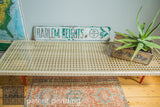 Long wooden Mod Sled Table featuring an intricate grid and bright red legs.