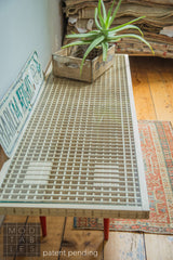 Angled view along the length of the Mod Sled Table's wooden grid top under glass.