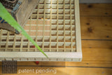 Corner view of a handmade wooden table showing the intricate slat grid beneath the glass.