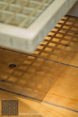 A distinct grid-like shadow cast by the slatted wooden Mod Sled Table.