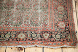 Softened colors and intricate boteh pattern on a distressed antique Senneh rug corner.