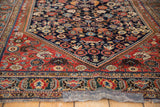 Detailed view of the antique Qashqai rug's dense, jewel-toned patterns on navy and red.