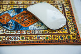 White mouse on geometric antique Heriz style mouse pad with rust and blue.