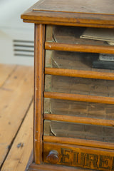Victorian Eureka spool cabinet showing aged oak wood and cracked glass drawer.