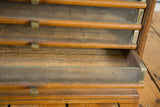 Open drawer detail of an antique Eureka silk spool cabinet showing wood patina and glass.