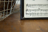 Corner of vintage eye chart plaque showing musical notation and 1935 copyright.