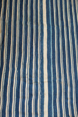 Supple hand-woven indigo textile with variegated blue and cream vertical stripes.