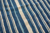 Hand woven indigo textile with varied blue and off-white stripes, featuring subtle textures.