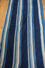 Hand-woven indigo striped textile, showing natural dye variation and textured vintage wear.