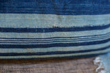 African indigo pillow detail: blue striped handwoven textile with visible mending.