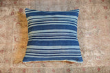 Angled view of the indigo pillow, highlighting its handwoven texture and varied blue stripes.