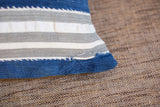 Corner of a vintage indigo mudcloth pillow, highlighting striped fabric and stitched wear.