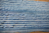 Hand-woven collectible African indigo textile with varied blue stripes and soft texture.