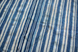 Hand-woven indigo throw, showing varied blue and off-white stripes and stitched seams.