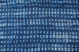Vintage indigo textile detail showing hand-dyed white dash motifs and woven texture.