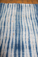Detail of hand woven vintage African indigo textile with intricate resist-dyed blue stripes and cotton texture.