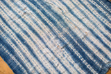 Hand-woven indigo textile with variegated blue stripes and natural patina.