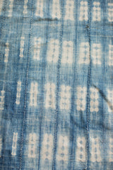 Hand-woven indigo textile featuring stitched panels and abstract white patterns.