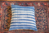 Faded indigo blue pillow with handwoven texture and irregular white batik stripes.