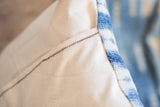 Lumbar pillow's cream canvas envelope enclosure with dark zigzag stitch.