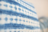 Close-up of faded indigo blue handwoven Batik textile with textured diamond pattern.
