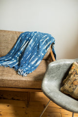 Vintage African indigo textile displaying hand-dyed blue and white patterns, supple texture, fringed edge.