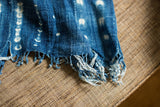 Frayed edge detail of the vintage hand-woven indigo blue textile with irregular patterns.
