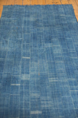 Hand woven vintage indigo textile showing varied blue tones and intricate woven texture, with a faint orange fleck.