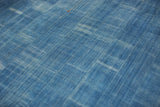 Textured close-up of a hand woven indigo blue textile with natural dye variations.