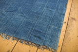 Hand-woven indigo collectible textile's soft texture, subtle vertical stripes, and fringed corner.