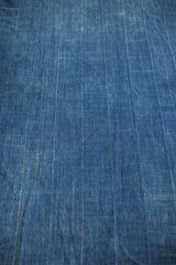 Close-up of vintage indigo textile, showing its hand woven texture and faint vertical stripes.