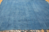 Close-up of hand-woven indigo cotton textile, featuring vertical stitched lines and fringed edge.