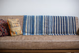 Handwoven vintage indigo textile with varied blue and off-white vertical stripes.