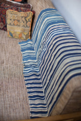 Hand-woven vintage indigo throw with varied stripe pattern, showing a stitched edge.