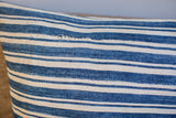 African indigo pillow, close-up of striped dark blue and off-white textile with visible stitching.
