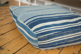 Vintage indigo floor pillow corner, showing varied blue stripes and textured textile.