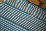 Light blue and off-white striped African indigo pillow, showing hand-stitched seam.