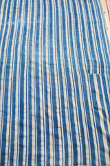 Hand-woven indigo and cream striped textile showing subtle vintage character and texture.