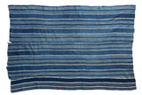 Vintage African indigo hand-woven textile throw featuring varied blue and beige stripes.