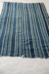 Hand woven African indigo textile featuring blue and natural stripes, highlighting textural character and wear.